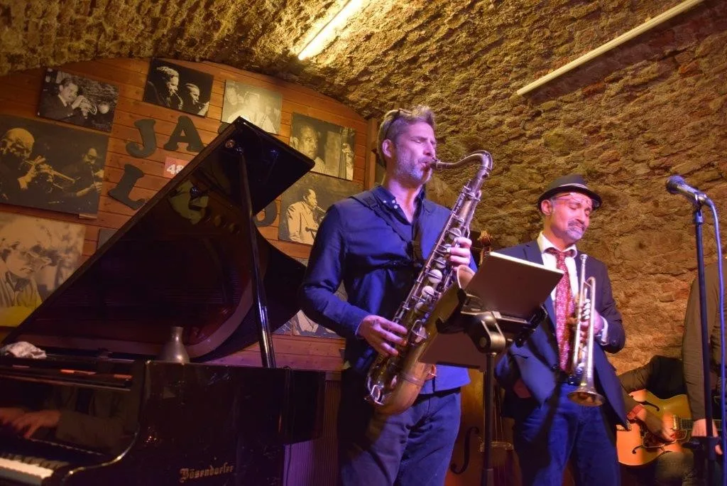 Two musicians performing in a jazz club, saxophone and trumpet.
