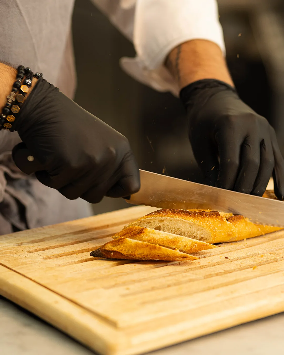 A chef slicing fresh bread on a wooden board.