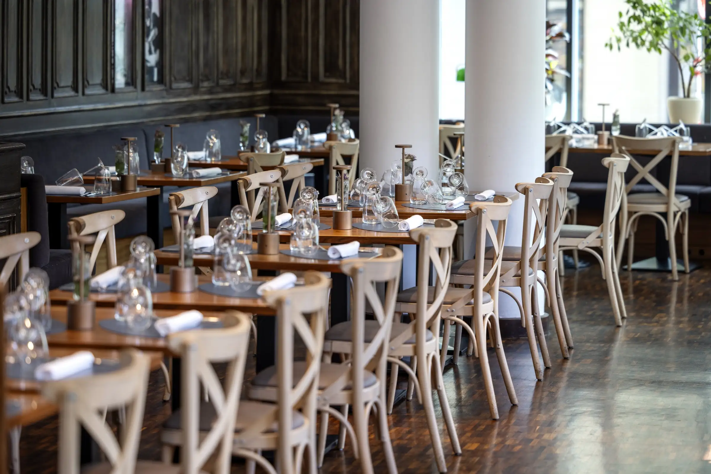 Gemütlicher Gastraum im Restaurant mit eleganten Tischen, Stühlen und stilvollem Holzinterieur, ideal für ein entspanntes Essen.
