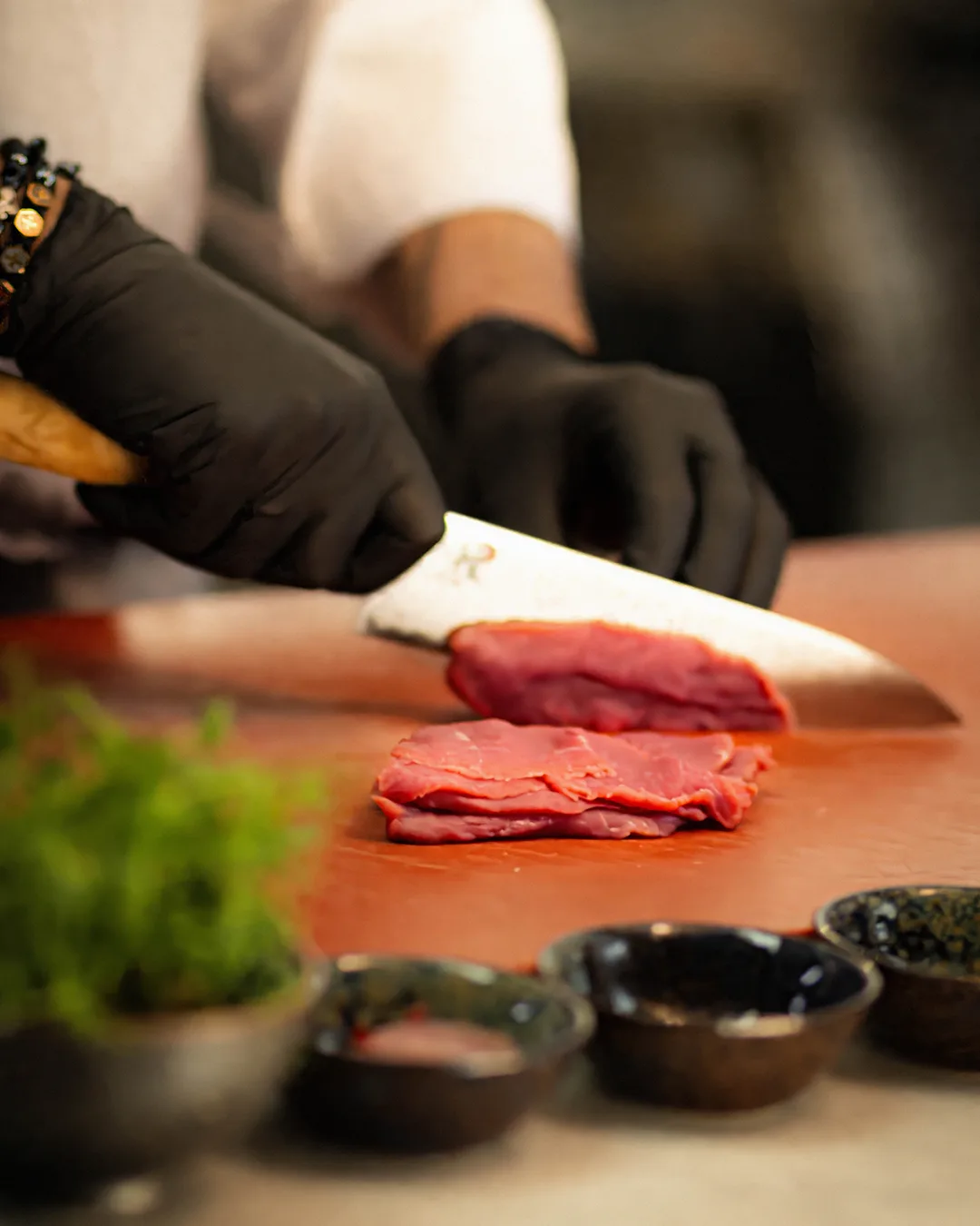 A chef is slicing fresh meat with a large knife.
