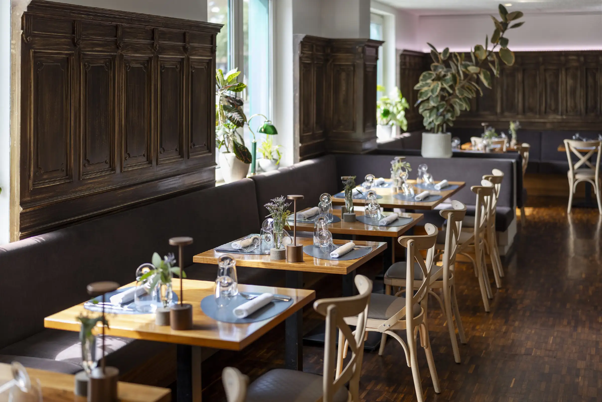 Gemütlicher Gastraum im Restaurant mit eleganten Tischen, Stühlen und stilvollem Holzinterieur, ideal für ein entspanntes Essen.
