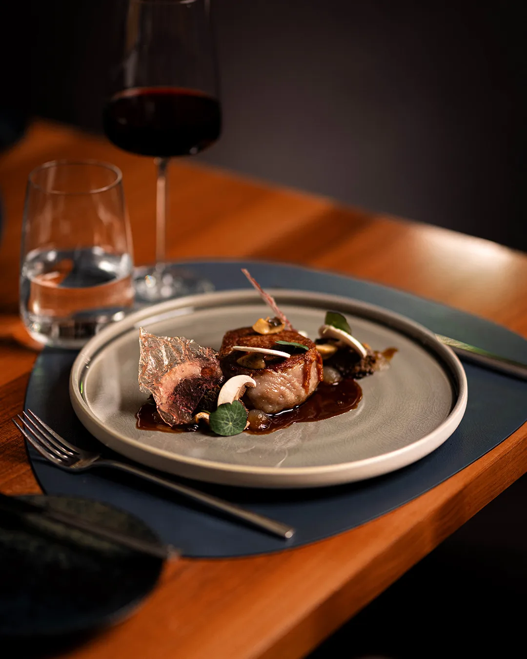 A beautifully arranged gourmet dish with meat, mushrooms, and sauce on a plate.