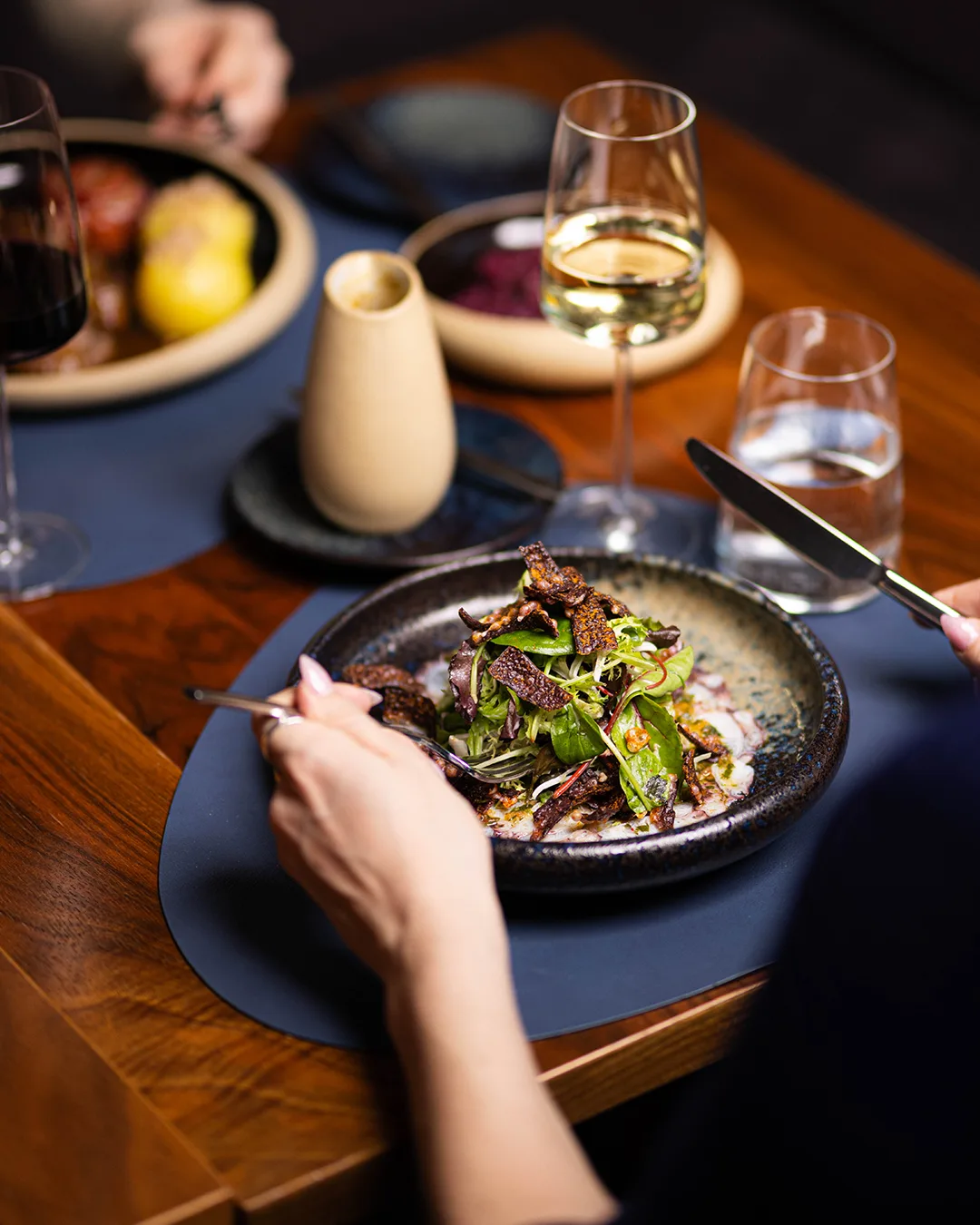 A gourmet dish with salad and crispy ingredients on a table.