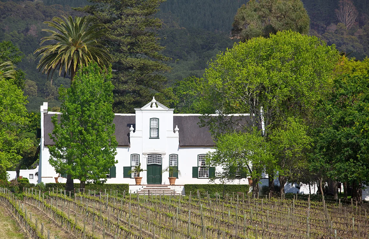 A historic winery surrounded by vineyards and trees.