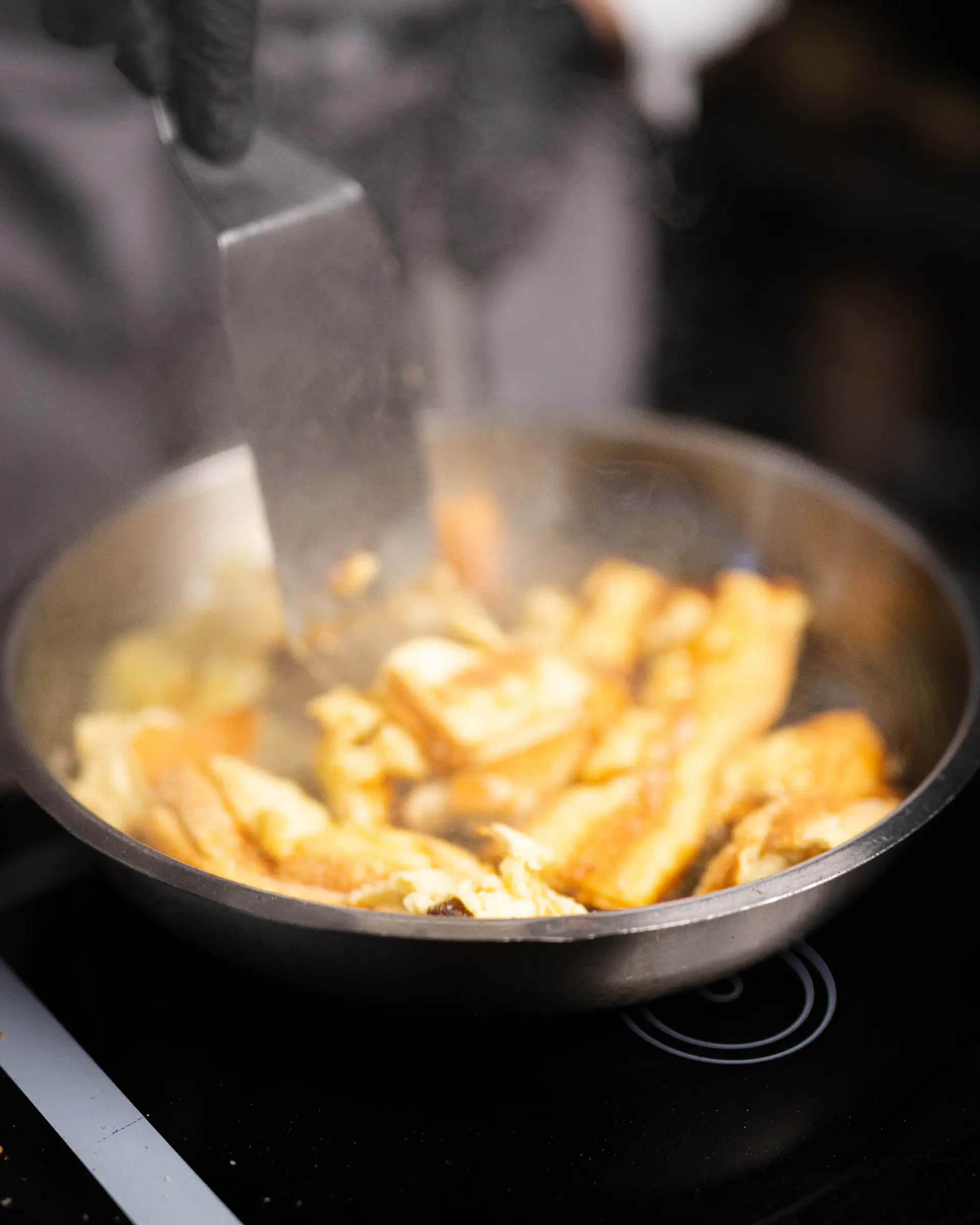 Kaiserschmarrn in a pan, freshly prepared in the restaurant kitchen, surrounded by steam.