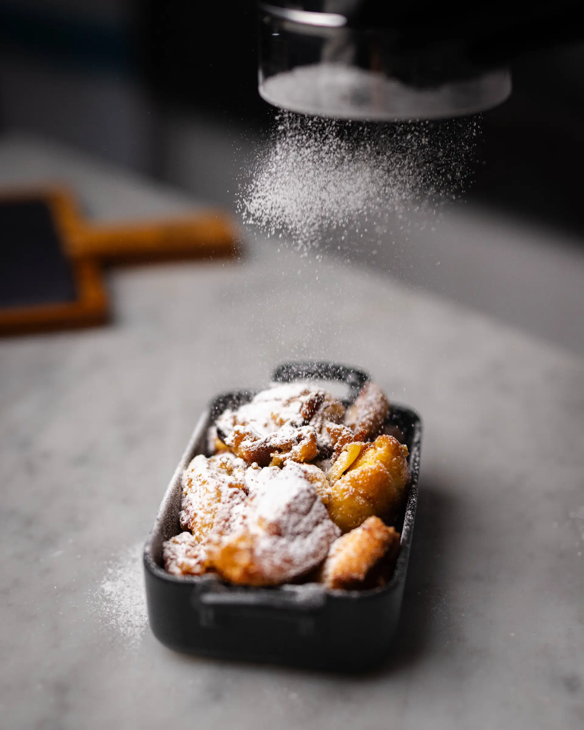 Kaiserschmarrn with powdered sugar in a black bowl, freshly prepared in the restaurant.