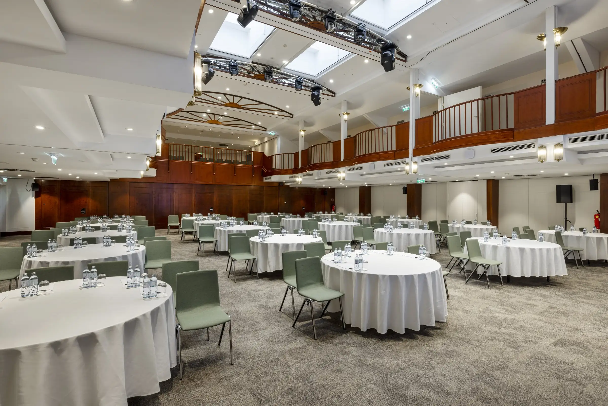 Geräumiger Tagungsraum im Restaurant mit runden Tischen, Stühlen und Wasserflaschen, ideal für Meetings und Veranstaltungen.