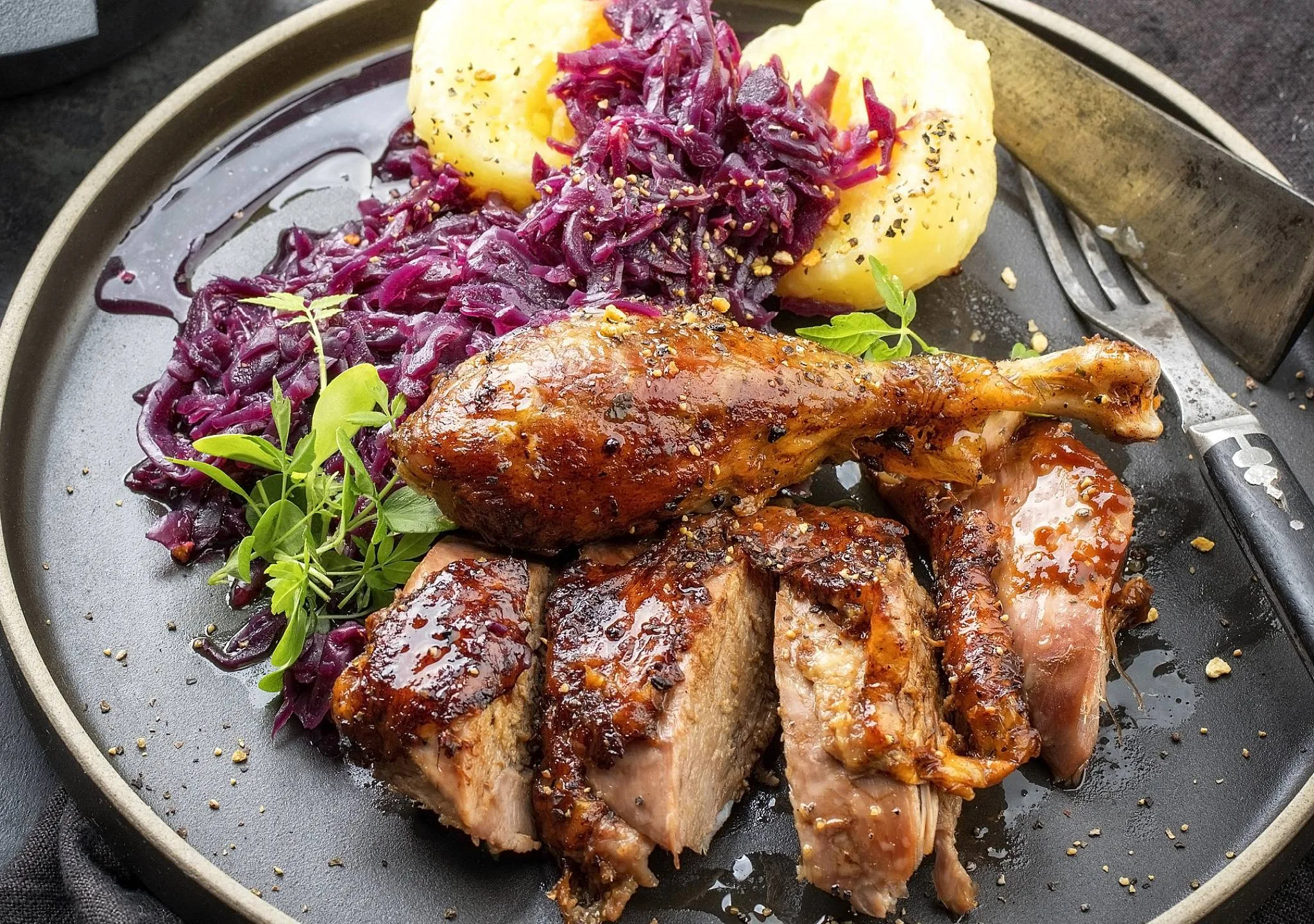 A plate with goose, red cabbage, and potatoes.