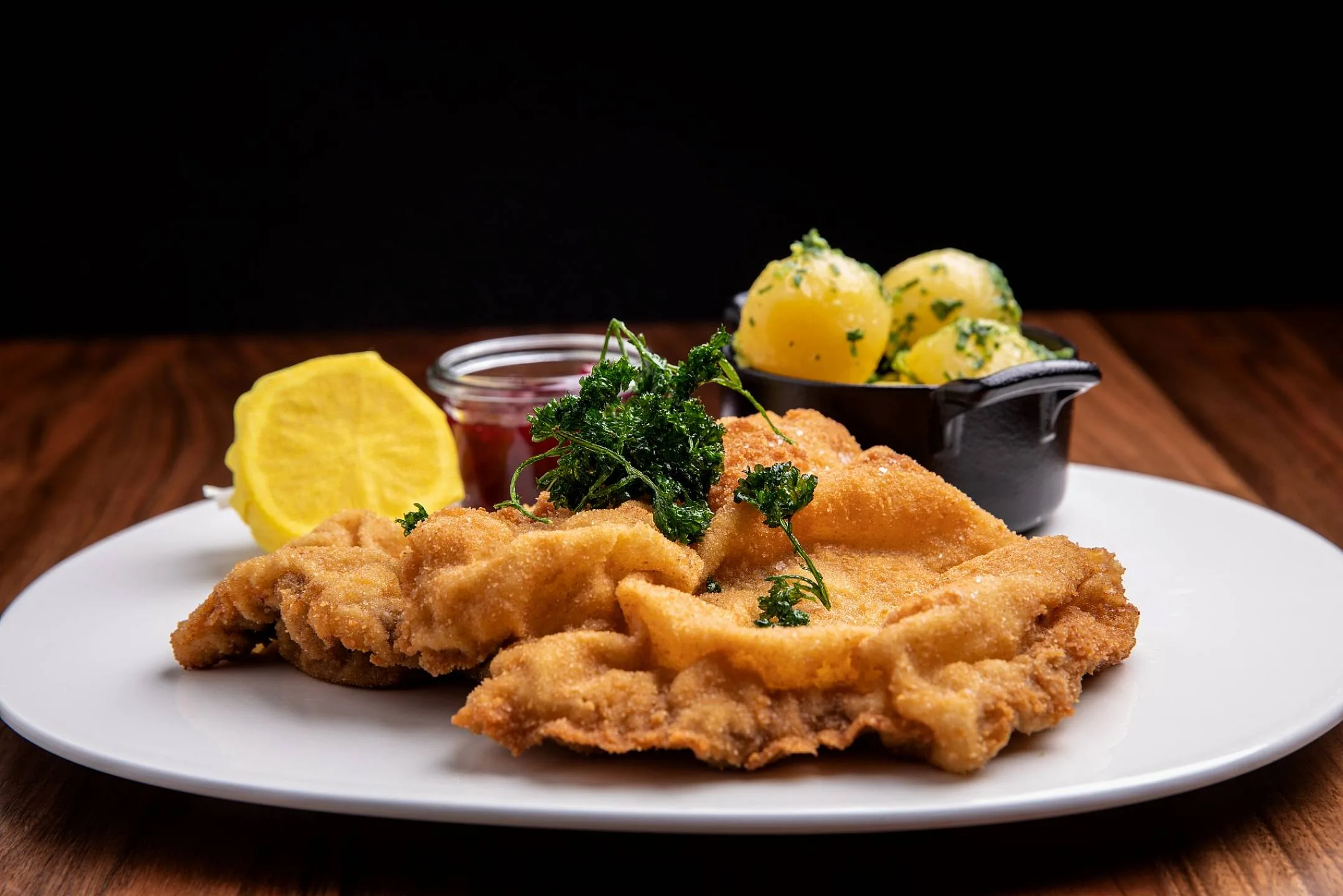 Wiener Schnitzel on a plate with lemon and potatoes.