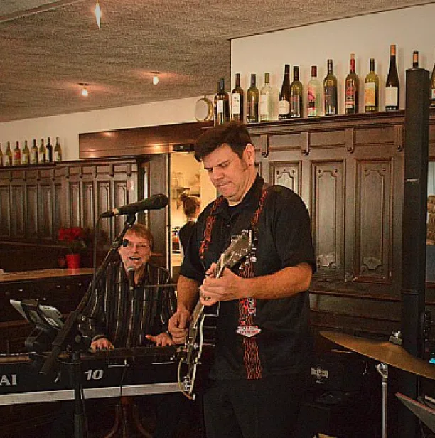 Zwei Musiker spielen live im Restaurant, einer am Keyboard und der andere mit einer Gitarre.